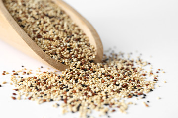 Closeup of scoop with raw quinoa grains on white background