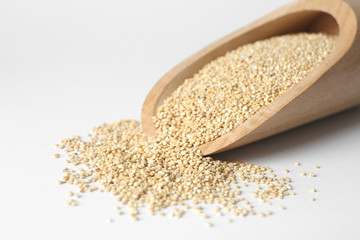 Scoop with raw quinoa grains on white background, closeup