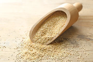Tuinposter Scoop with raw quinoa grains on wooden background © Africa Studio