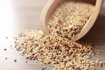 Wandcirkels aluminium Closeup of scoop with raw quinoa grains on wooden table © Africa Studio