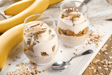 Glasses with yummy banana pudding on wooden board