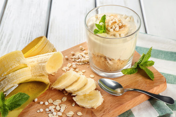 Glass with yummy banana pudding on wooden board