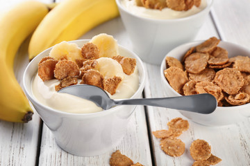 Bowl with yummy banana pudding and flakes on wooden table