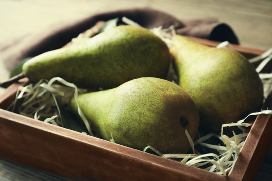 Ripe pears in wooden box on table