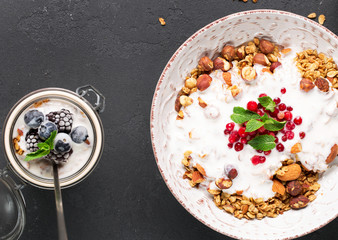 Granola with yoghurt, blueberries and blackberries in a white plate on a black background, selective focus, horizontal