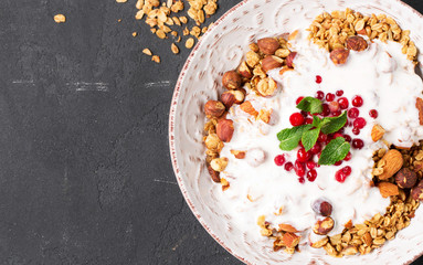 Granola with yoghurt, blueberries and blackberries in a white plate on a black background, selective focus, horizontal