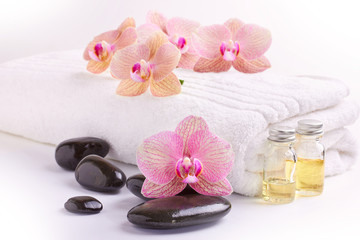 Obraz na płótnie Canvas Pink orchids, moisturizing oils and spa stones on white
