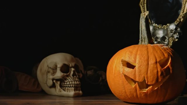 Carved Halloween pumpkin lights inside with flame and skuls around.