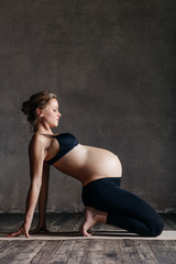 Fototapeta na wymiar Young beautiful pregnant yoga posing in studio
