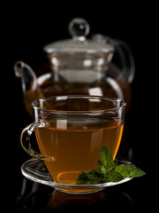 Fresh mint and green tea in a cup and a teapot from glass