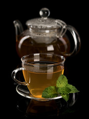 Fresh mint and green tea in a cup and a teapot from glass