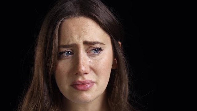 Studio Shot Of Unhappy Young Woman Crying Into Camera