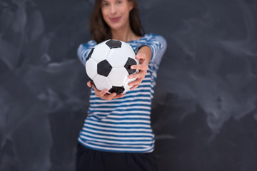 woman holding a soccer ball in front of chalk drawing board