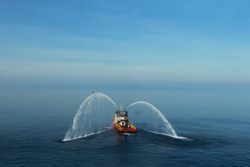 Fire hose boat is spraying water on the sea for supporting emergency case of fire of offshore oil...