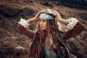fashion model portrait outdoors. boho style young woman with headdress made of feathers