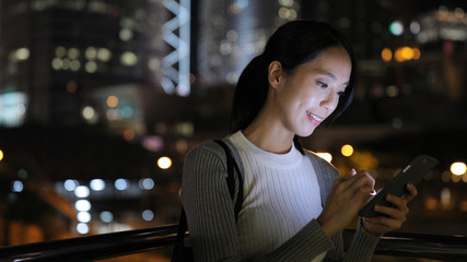 Young woman use of smart phone in city at night