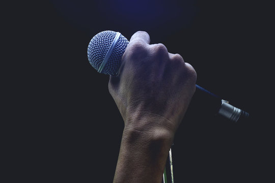 Man hands holding microphone on stand.