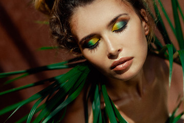 young beautiful woman with eyes closed on tropical background