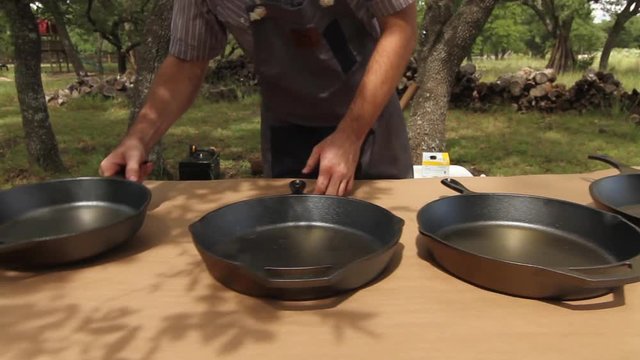 Person places cats iron skillets on table outside