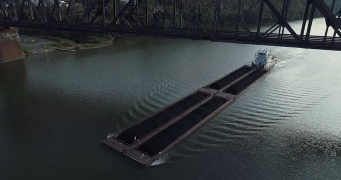 A coal barge travels on the Ohio River under a railroad trestle bridge.  	