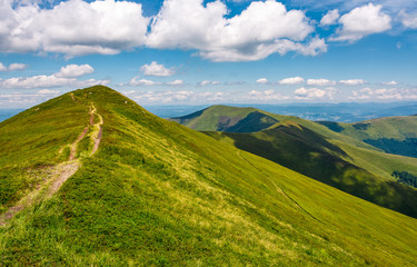 path through grassy meadow on hillside in summer. gorgeous mountain landscape in fine weather under blue sky with cloud