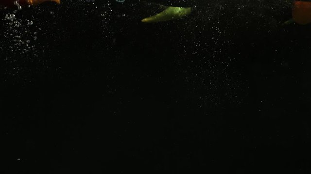 Paprika falling into water on black background. Bright high quality video.