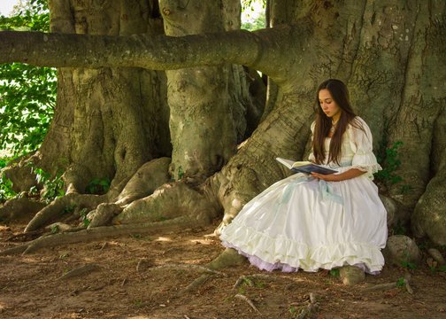 girl reading in white dress by trees