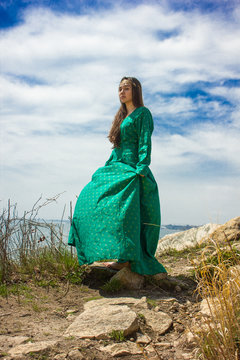 girl in green medieval dress on cliff
