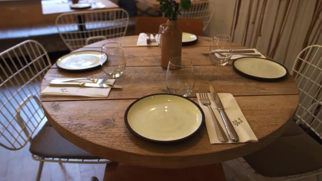 Zoom out shot of an empty table at a fashionable restaurant