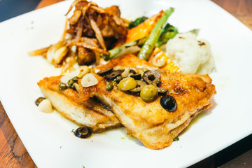 Grilled sea bass fish meat steak in white plate