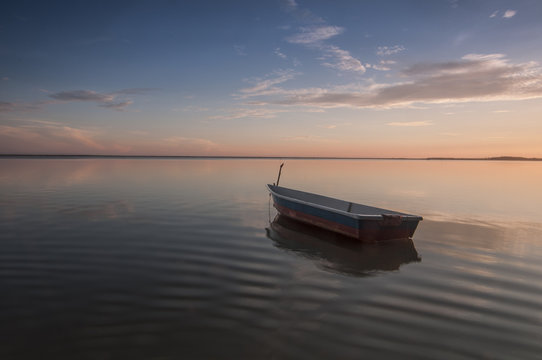 A small boat floats serenely on the sea water. The image contains soft focus when view at full resolution.