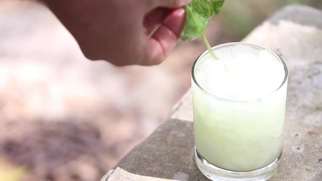 Person places mint in frozen mojito, close up