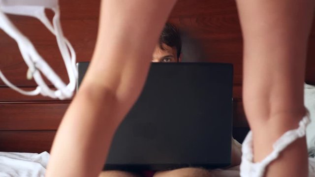 Sexy woman trying to seduce man working on laptop in bed. the girl takes off her underwear in front of her boyfriend, and he ignores her, works on a laptop. 4k, slow motion