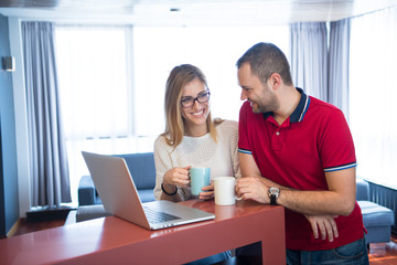 Fototapeta premium couple drinking coffee and using laptop at home