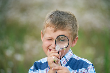 Boy looking at plant through magnifying glass