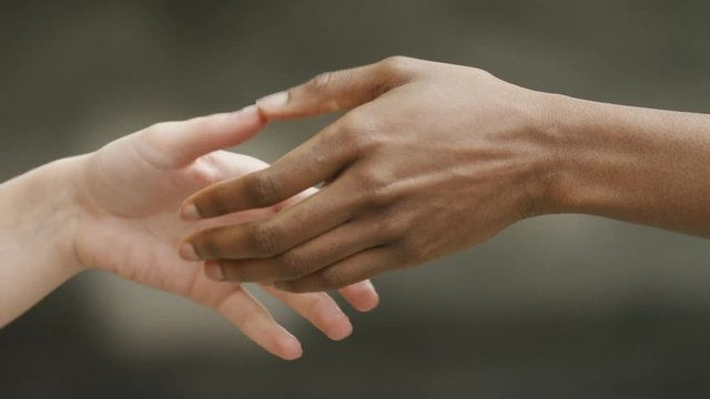 Two diverse hands come together for a handshake, in slow motion