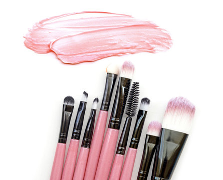 Pink color skin foundation beige cream paint stroke and brushes make up on background