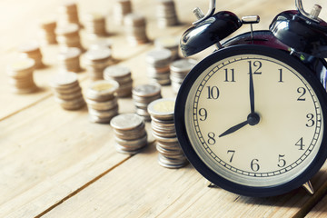Fototapeta na wymiar alarm clock and money coin on wood table, saving money concept