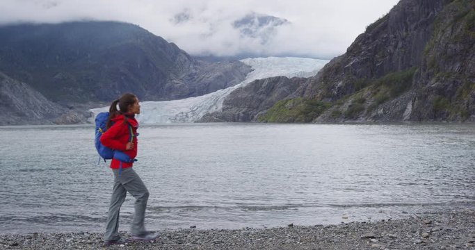 Tourist hiking woman in Alaska walking by Mendenhall Glacier landscape. Woman hiker on travel adventure trekking wearing backpack. RED EPIC SLOW MOTION.