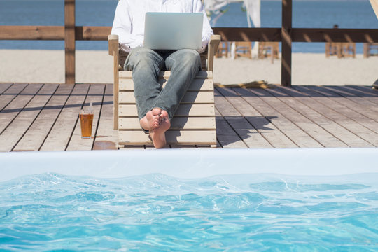 young men with laptopp working near the pool, freelancer in hotel on vacation with notebook