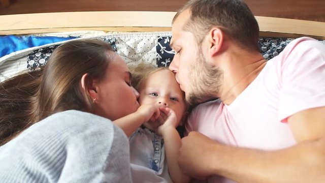 Happy young family hugging and kissing in the bedroom.