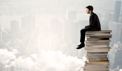 Student in city sitting on stack of books