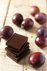A stack of chocolate slices and plums on a wooden table. Rustic style, selective focus.