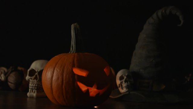 Carved Halloween pumpkin lights inside with flame and skuls around.