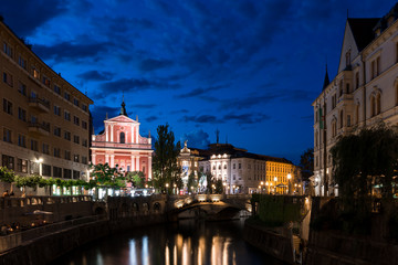 Fototapeta na wymiar Triple Bridge and Franciscan Church of the Annunciation in the center of Ljubljana at night illuminated water color reflection night sky