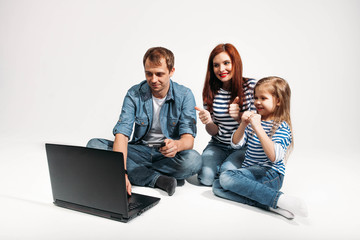 Happy family Father, mother and child lying on the floor with laptop credit card on white background isolated