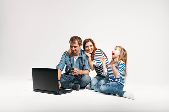 Happy family Father, mother and child lying on the floor with laptop credit card on white background isolated