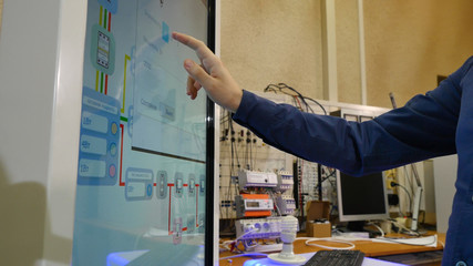 Man works on a touch screen. Young scientist uses a large touch screen to work