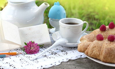 Breakfast with cup of coffee. Egg on white a lace tablecloth with green grass background. Note - good morning