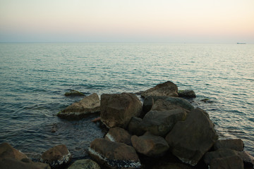 Fototapeta na wymiar large dark stones lying in the sea in the evening at sunset
